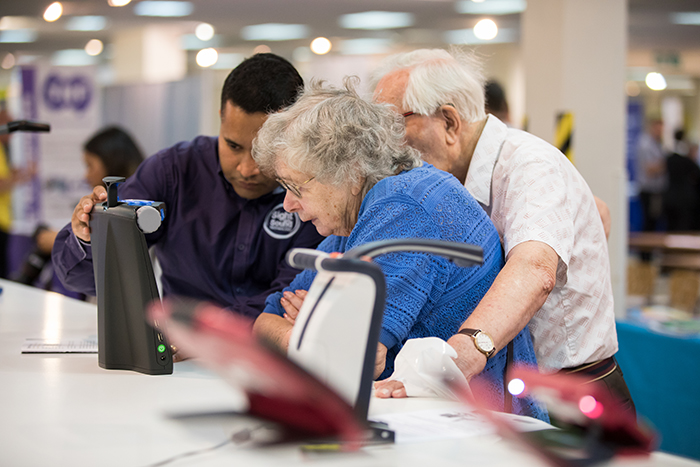 An exhibitor demonstrating a product to a couple at the Sight Village Central event